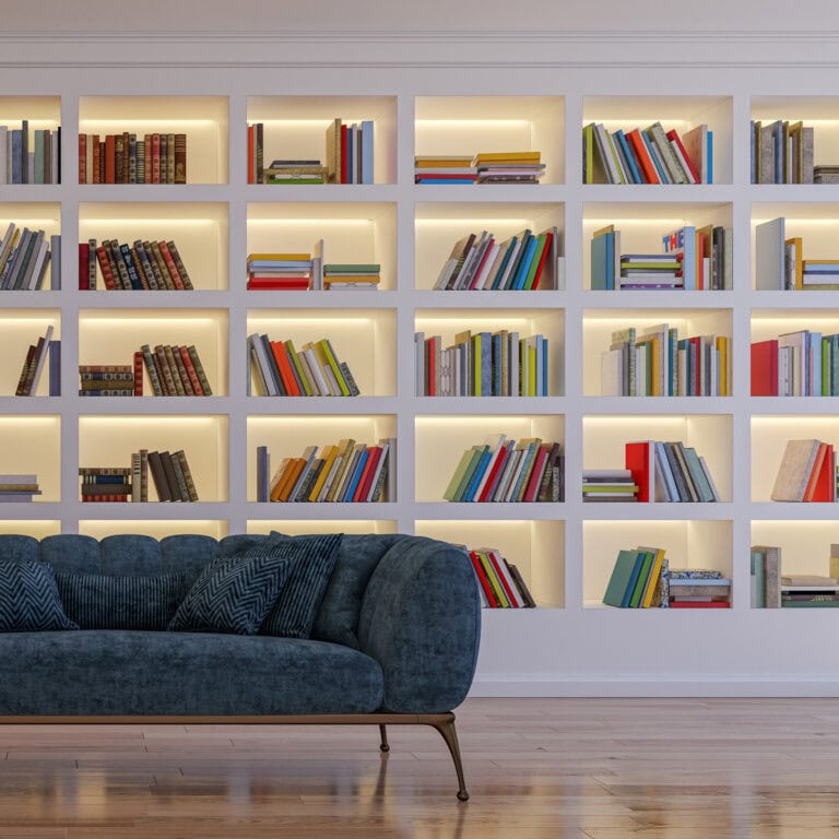 a blue sofa in front of a library wall with back lights