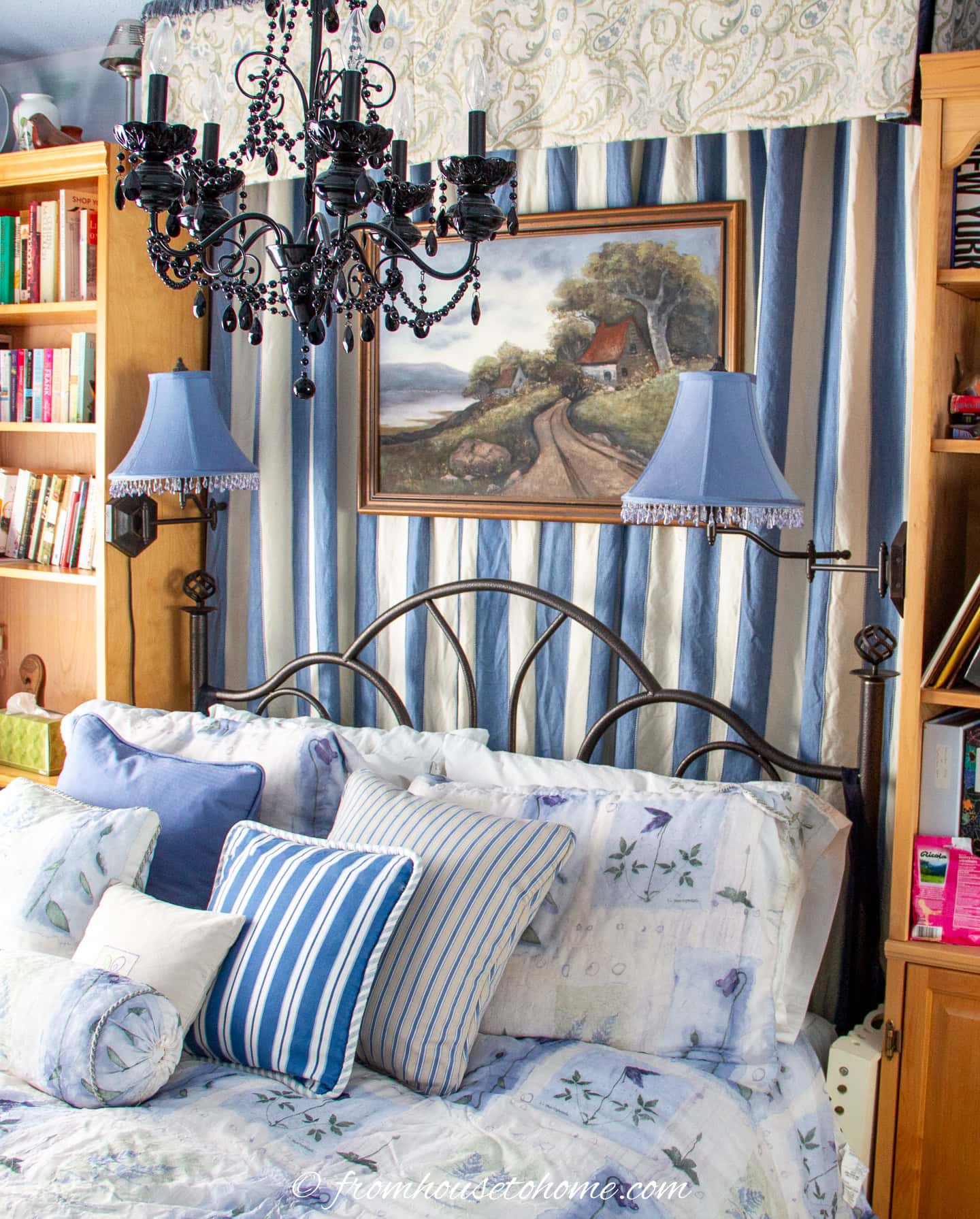 a cozy blue and white bedroom with curtains hung behind the bed