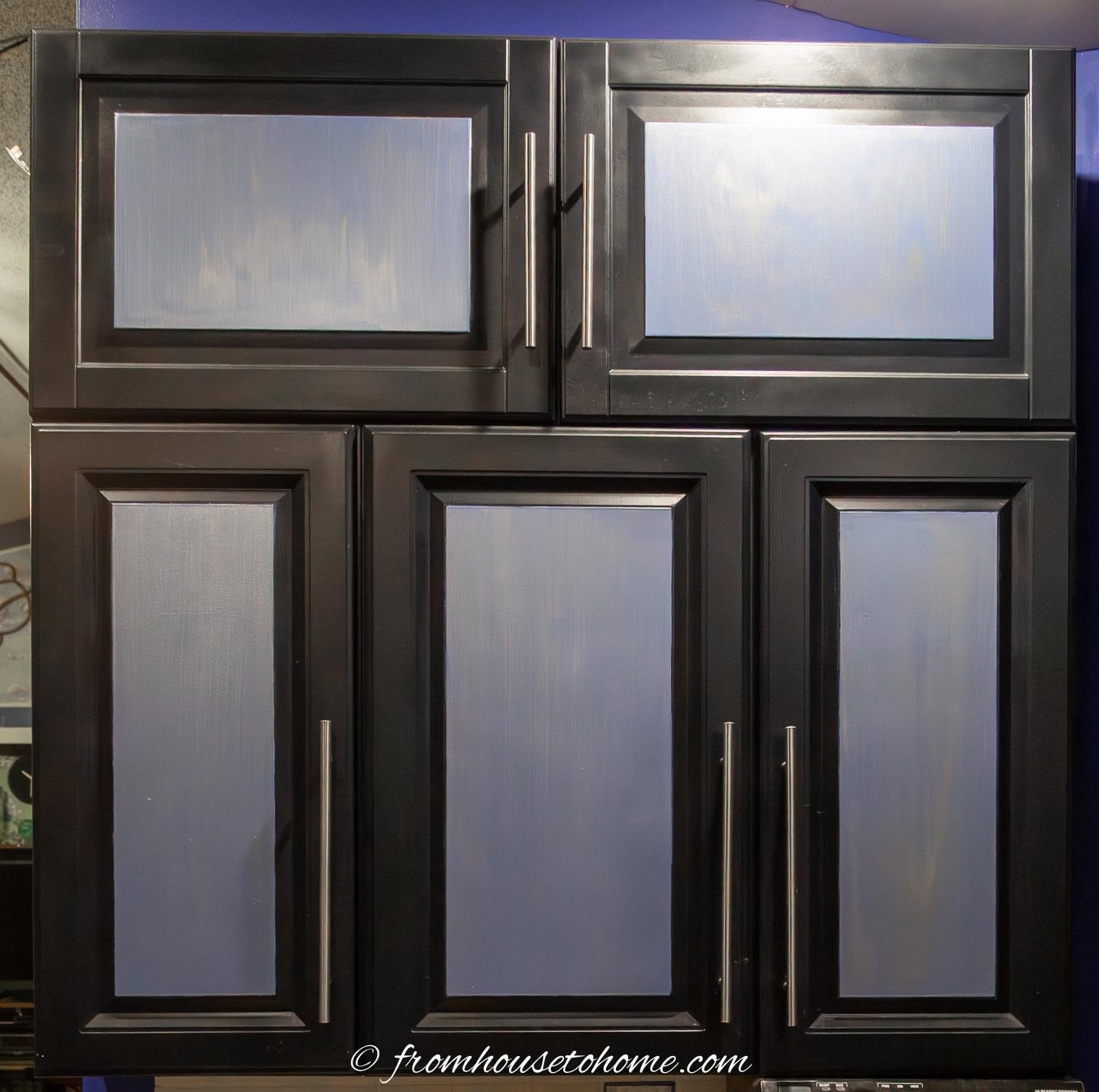 Wall-mounted kitchen cabinets with black frames and long brushed nickel handles