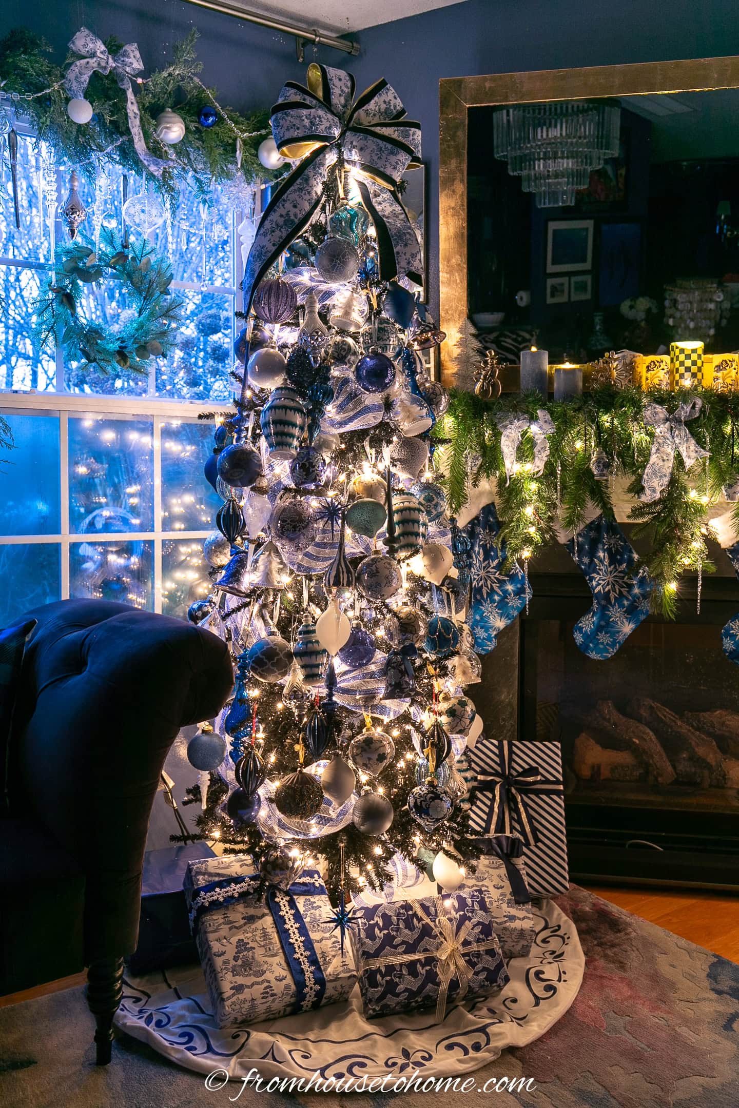 A Christmas tree decorated with dark blue and white ornaments surrounded by gifts wrapped with blue and white wrapping paper