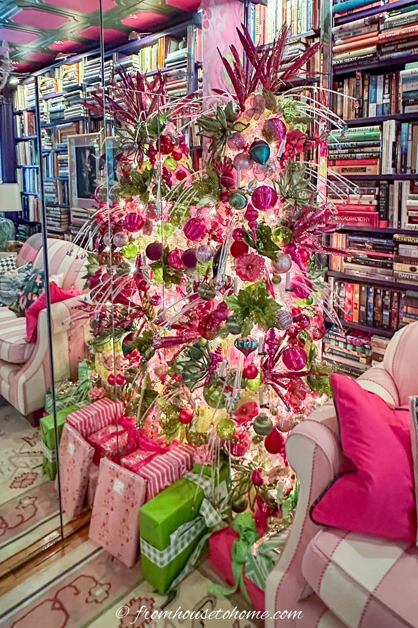 A white Christmas tree decorated with bright pink and lime green ornaments with presents wrapped in matching wrapping paper underneath it