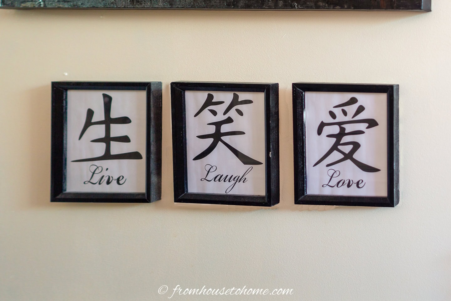 Three framed prints on a wall, each with a Chinese character and English translation: