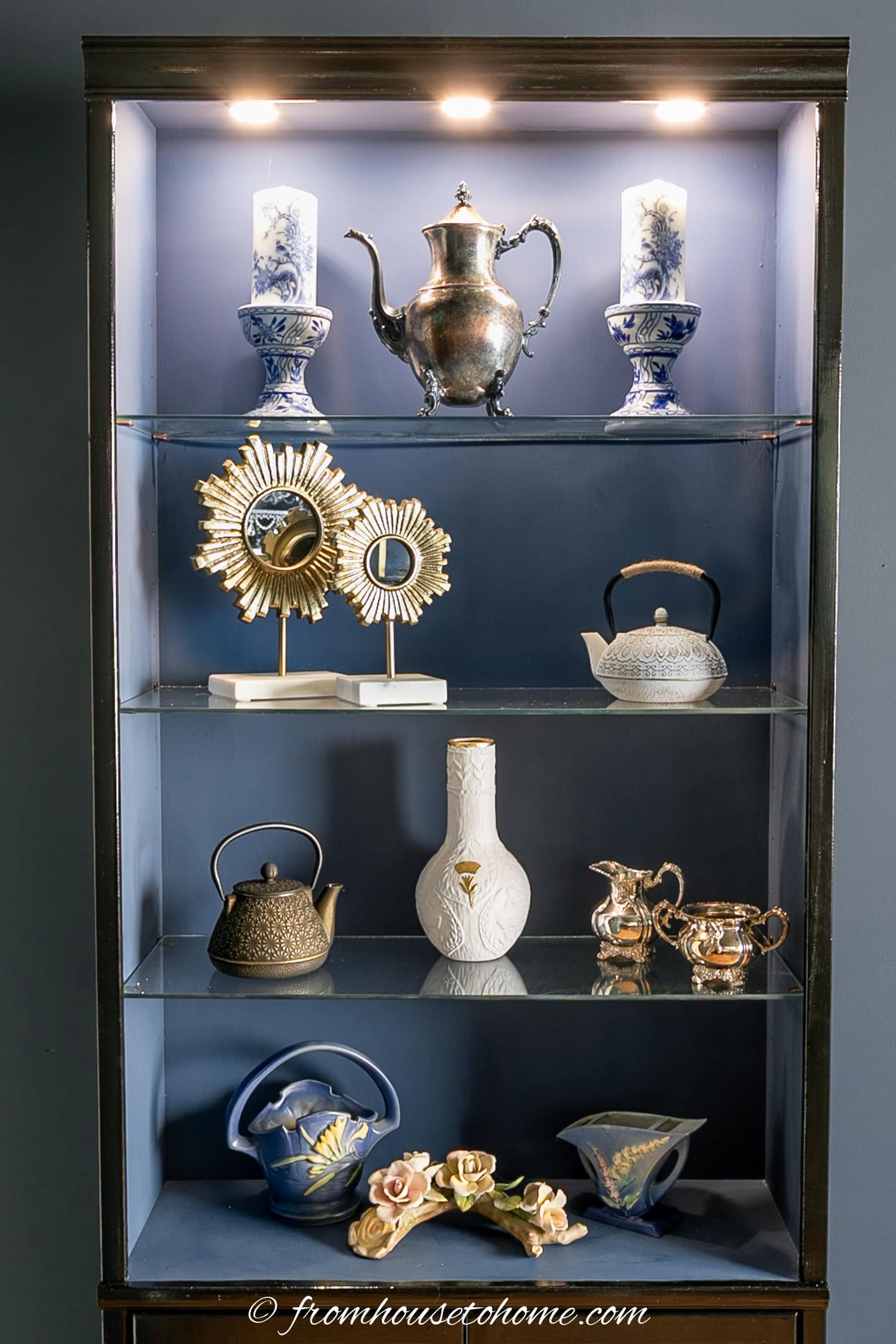 A bookshelf with lights at the top and glass shelves
