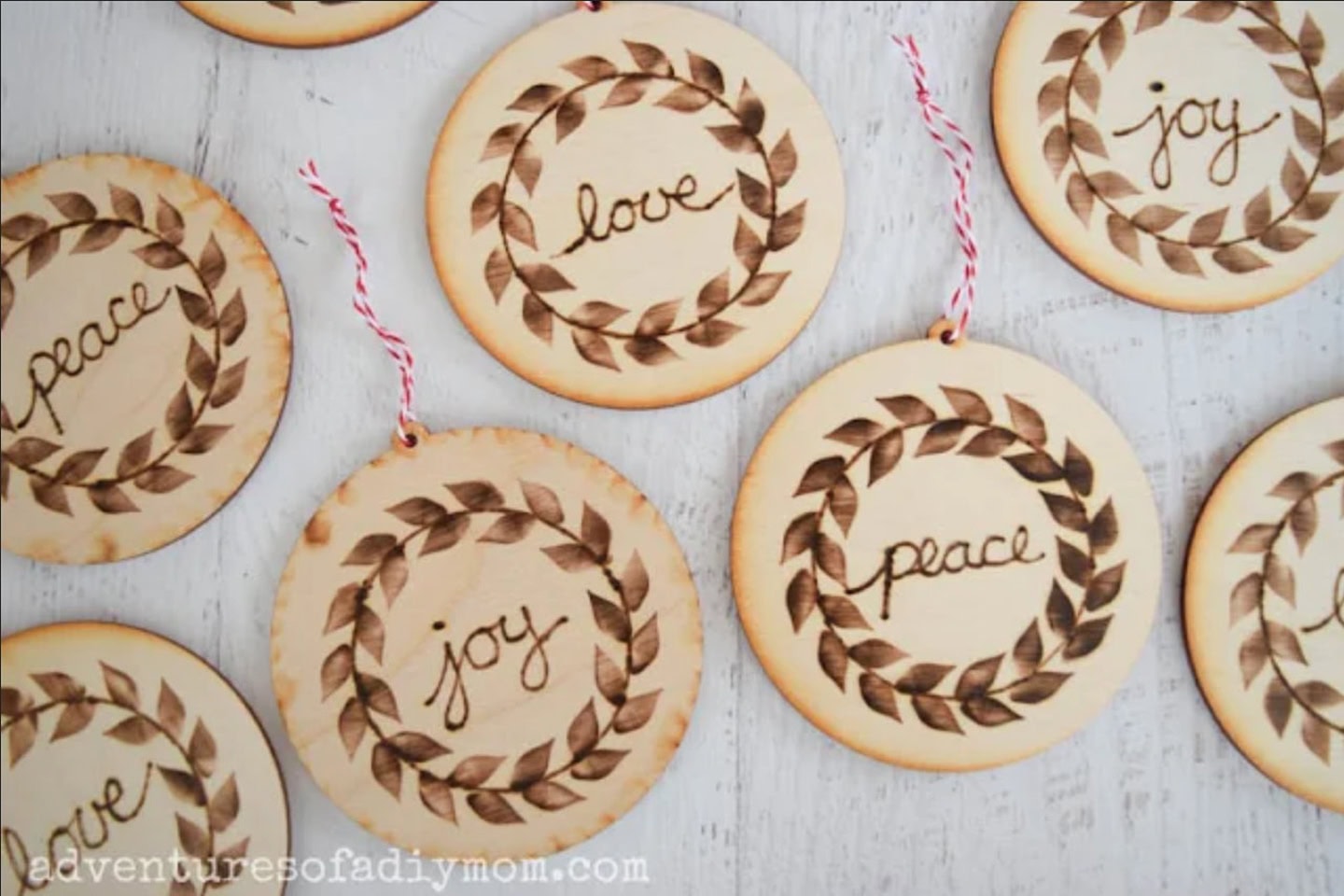 Round wooden ornaments with burned leaf wreath designs, each featuring the words