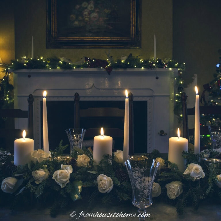 White candles, evergreens and white flowers as a Christmas centerpiece on a table