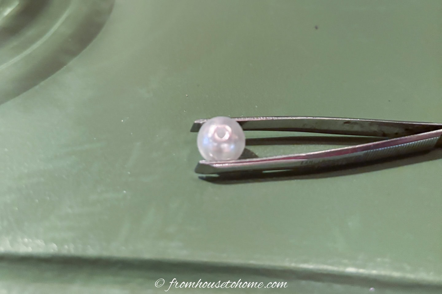 A pair of tweezers with a pearl in them