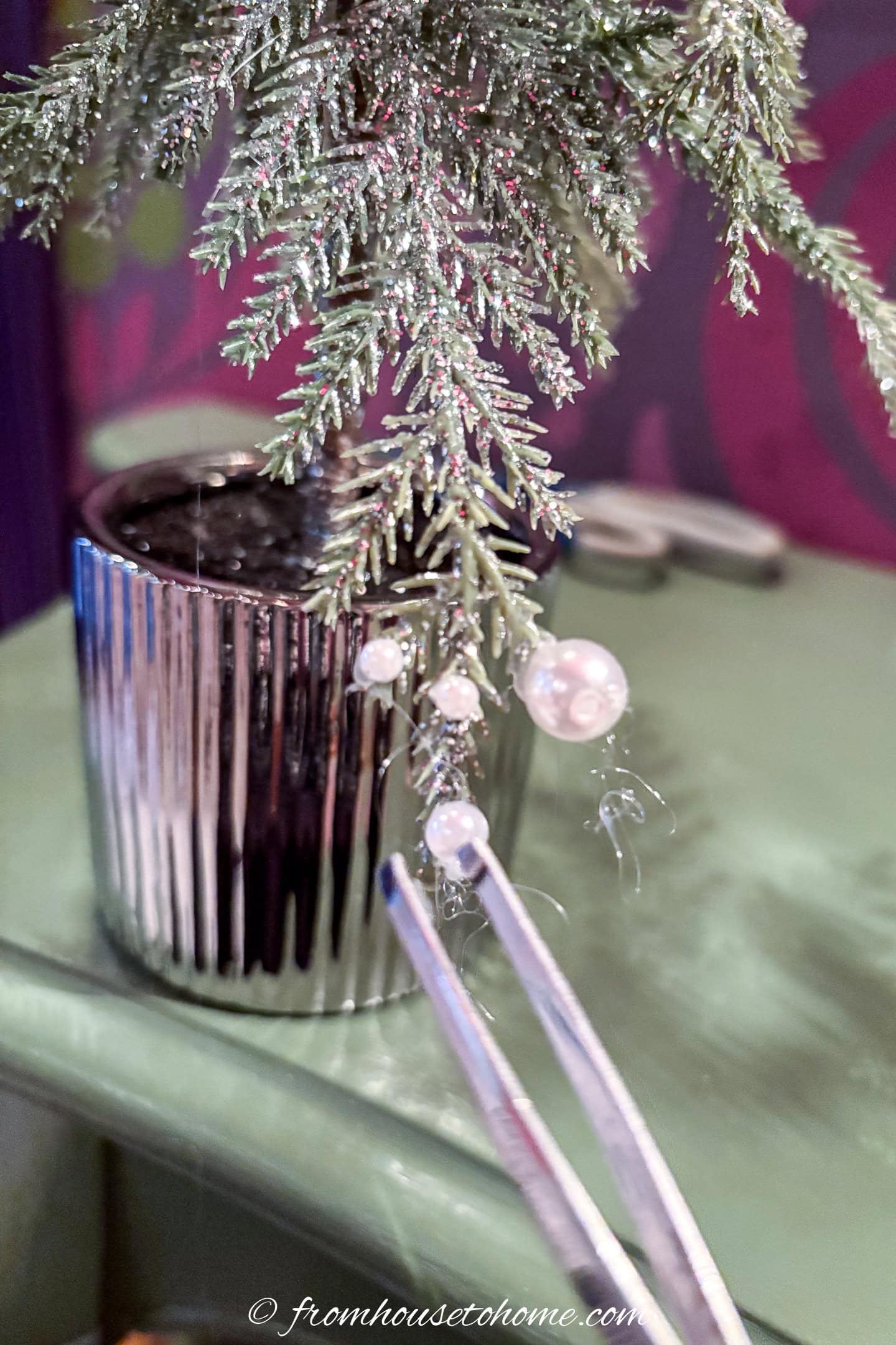A pearl being glued onto a tabletop Christmas tree