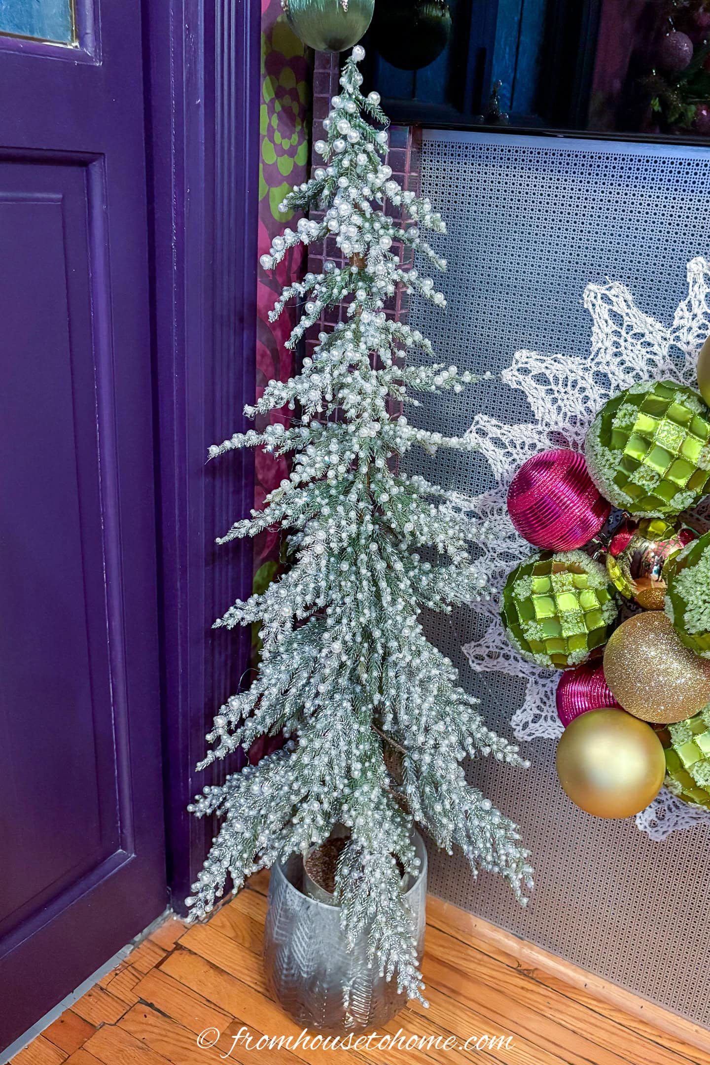 A DIY pearl christmas tree on the floor in front of a fireplace