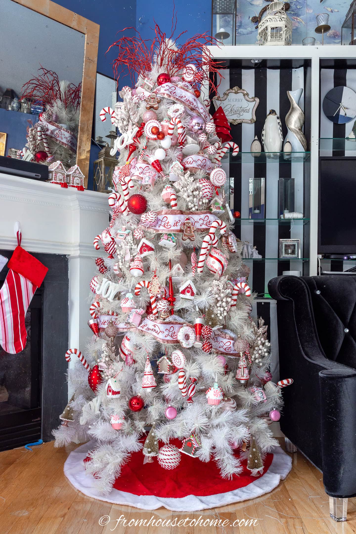 A red, pink and white candyland Christmas tree between a fireplace and a bookshelf in a living room