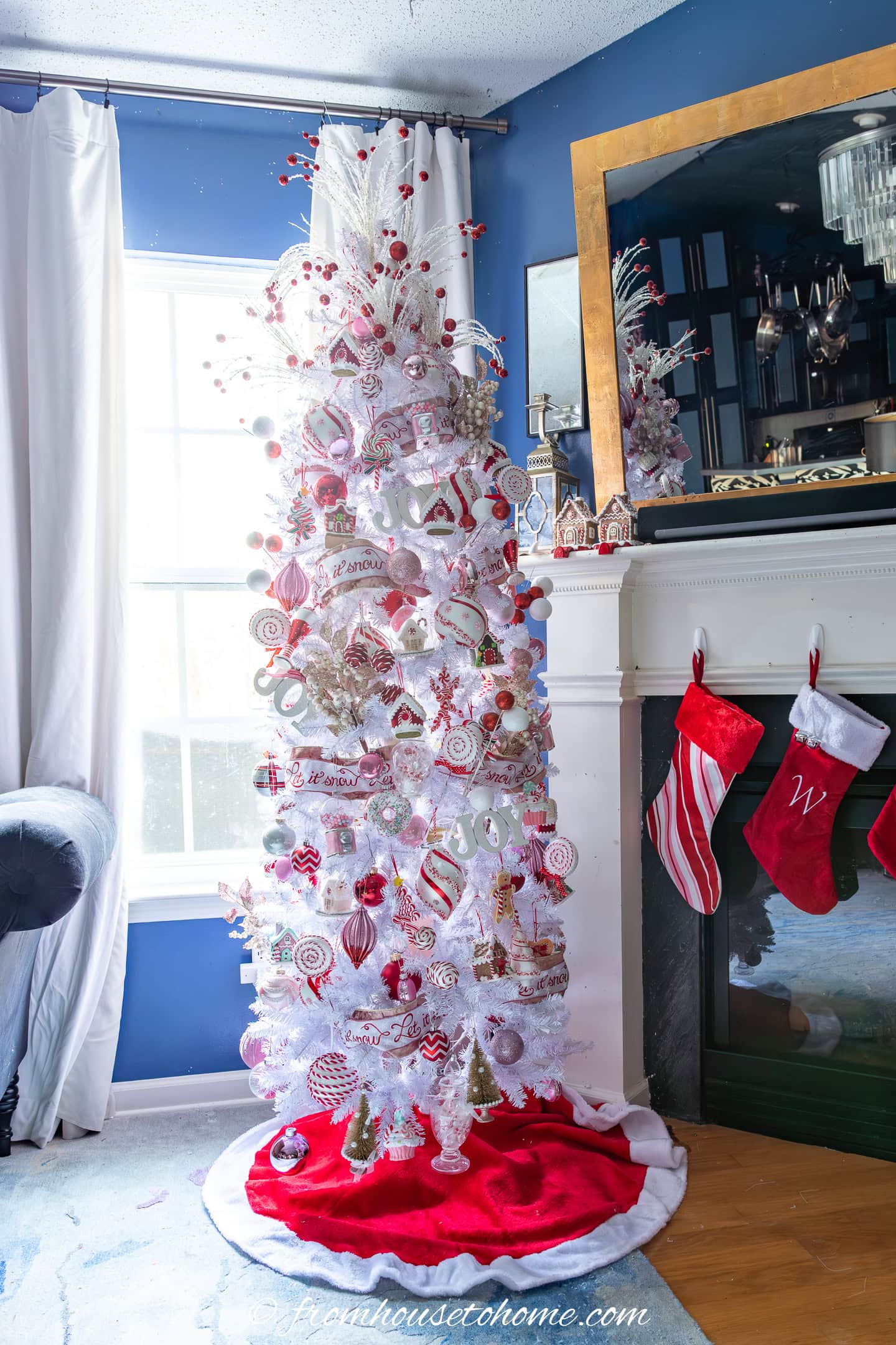 A slim white Christmas tree decorated in red, pink and white candyland ornaments