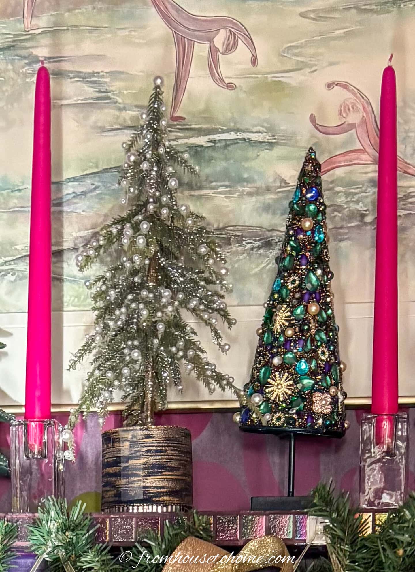 fuchsia taper candles on either side of mini Christmas trees on top of a mantel