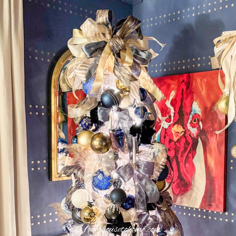 Close up of the top of a Christmas tree decorated with blue, white and gold ribbon and ornaments