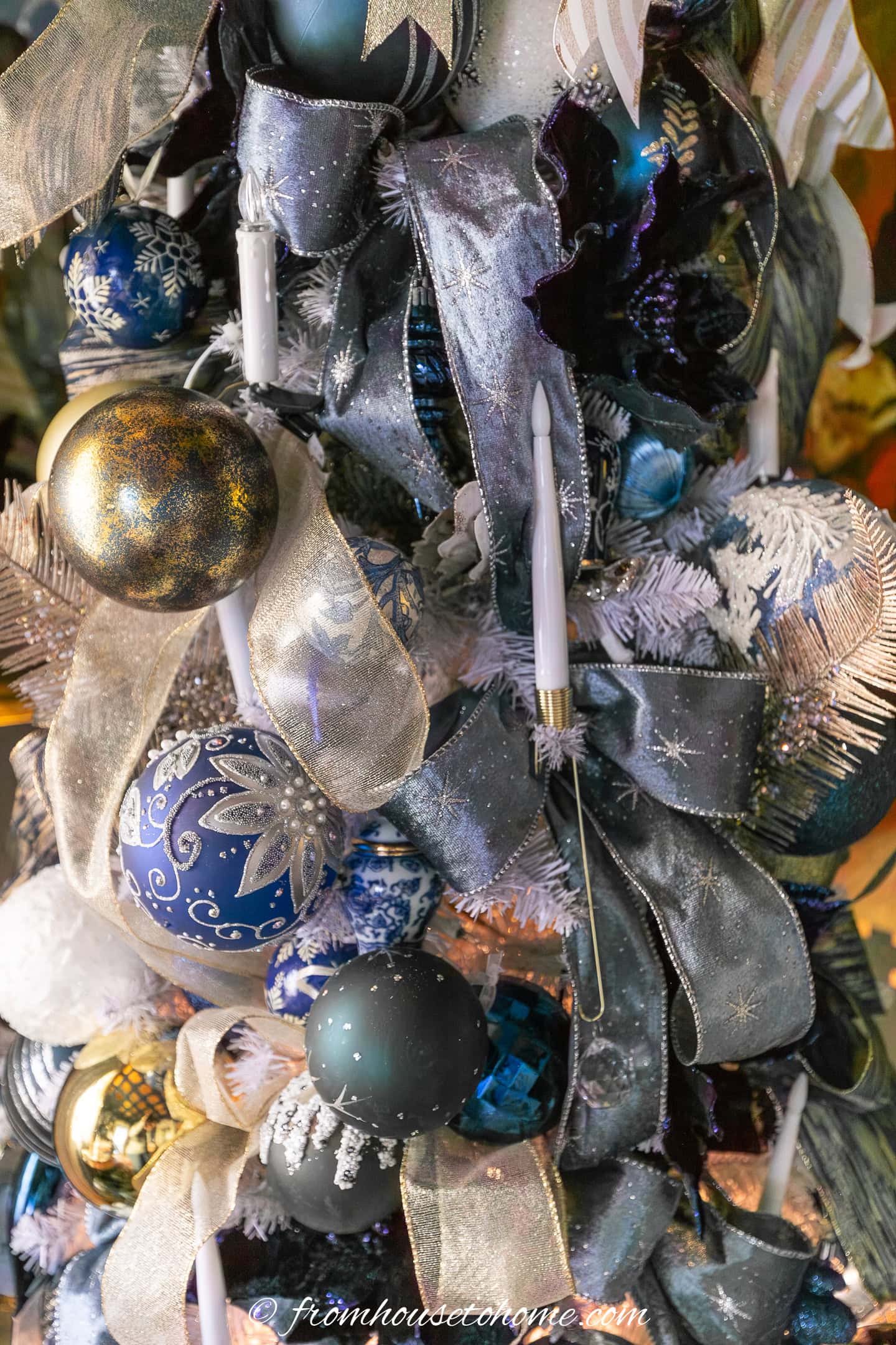 close up of ribbons and candles on a blue white and gold Christmas tree