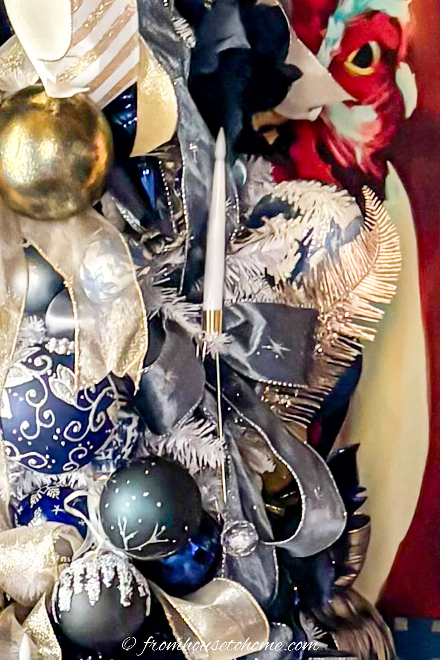 An LED candle in front of a bow on a Christmas tree decorated with ribbons and ornaments
