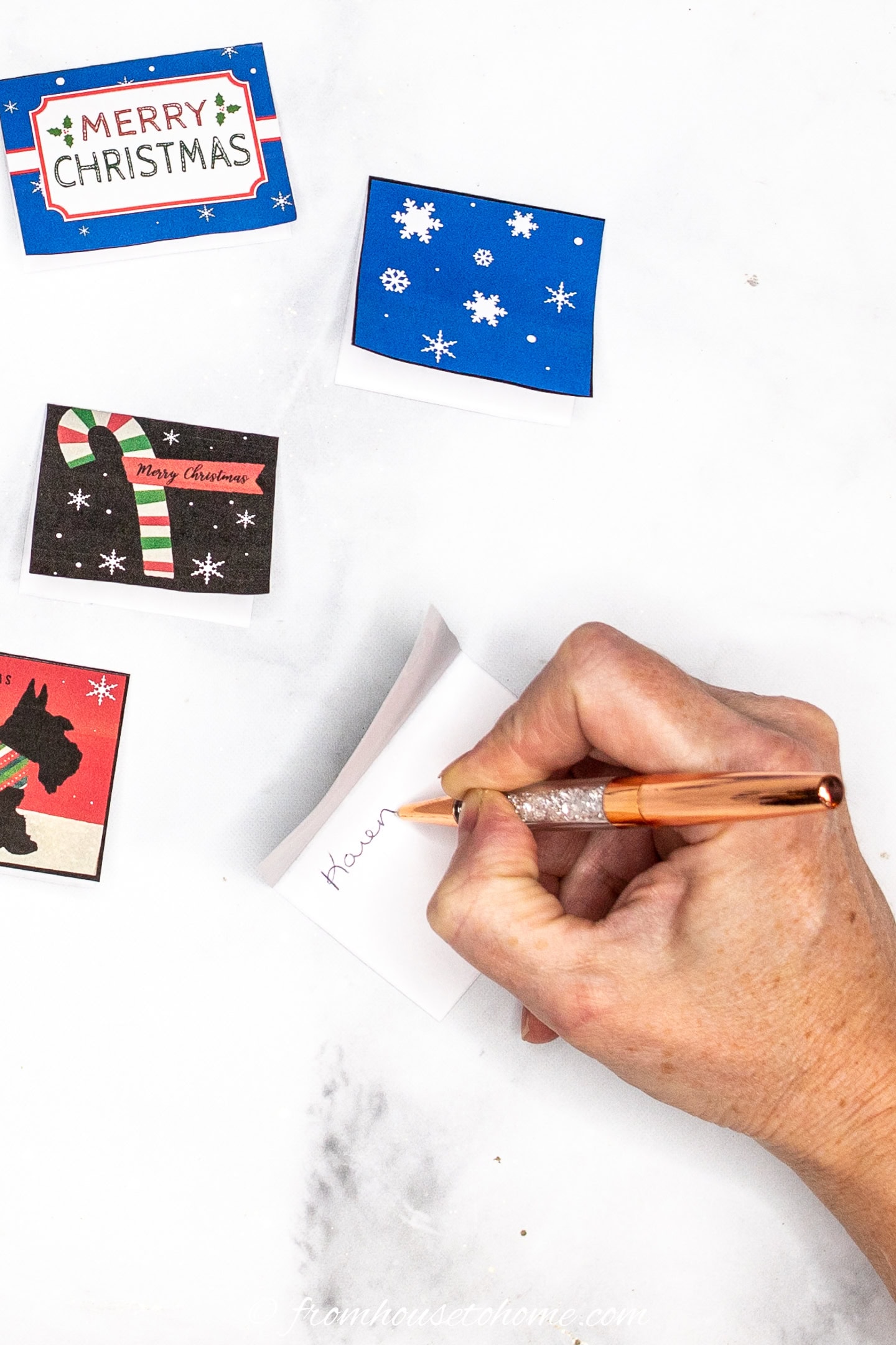 A folded Christmas gift tag being written in