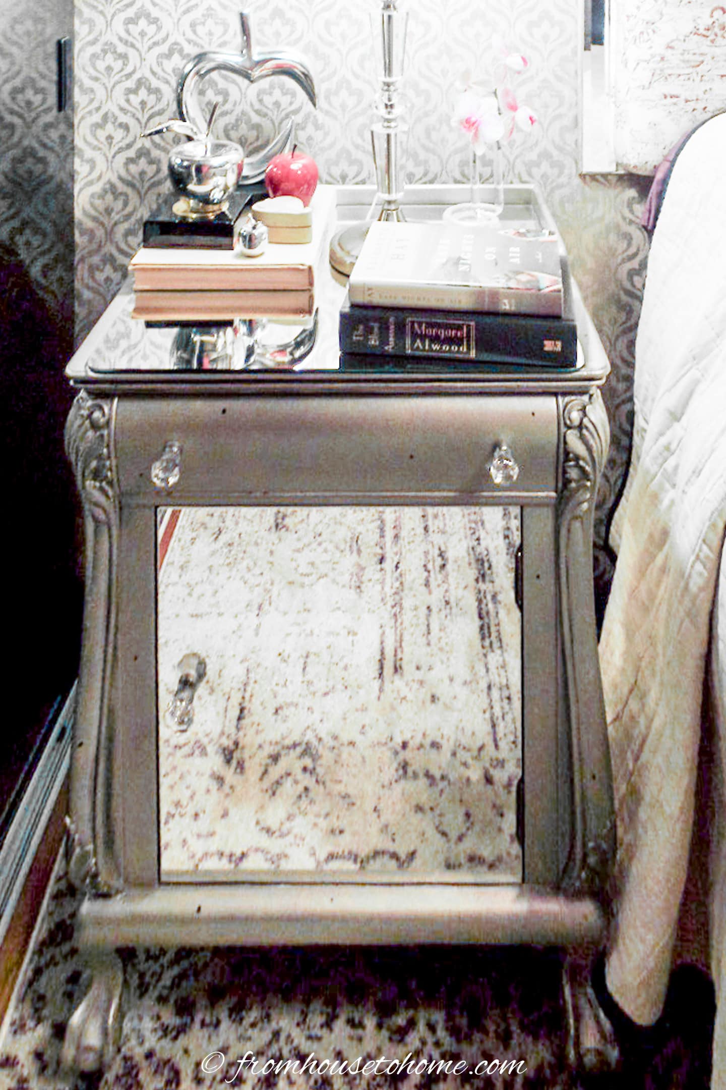 An old nightstand that has been painted silver with a mirror top and door