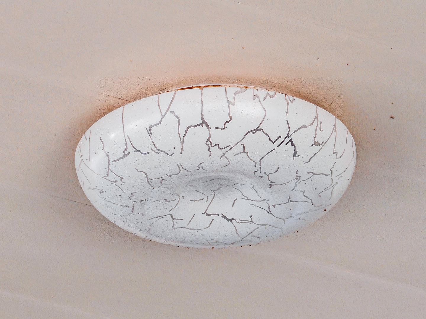 Close up of a flush-mount light fixture on a pink ceiling
