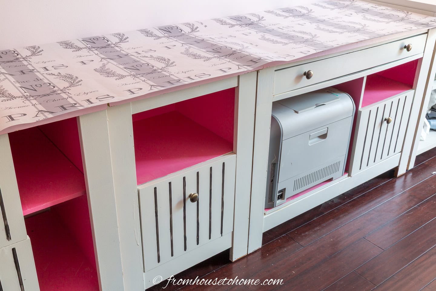 Filing cabinets painted white and pink with black pinstripes on the doors and a sheet of Paris-inspired wrapping paper on top