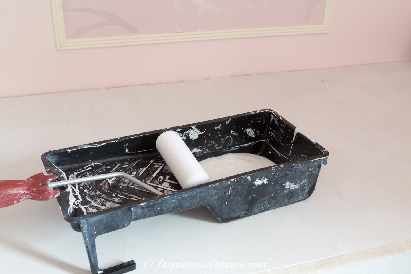 A small paint tray filled with wallpaper paste and a foam roller