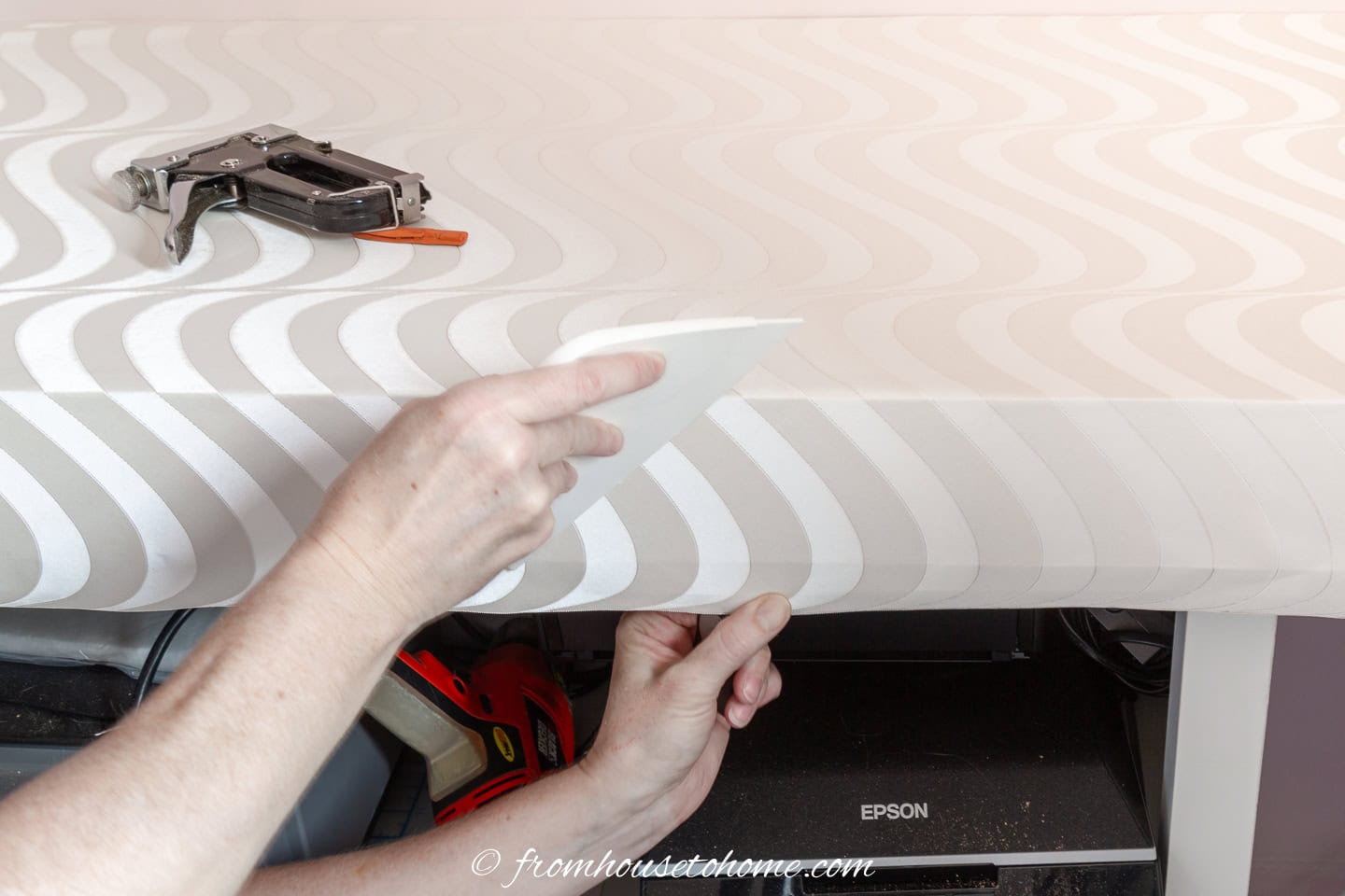 A smoother being used to stick wallpaper to the overhang on a countertop