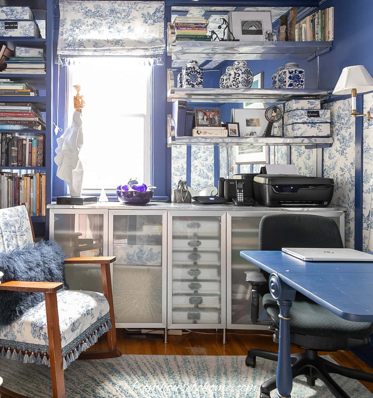 Shelves with glass doors in a small blue and white home office