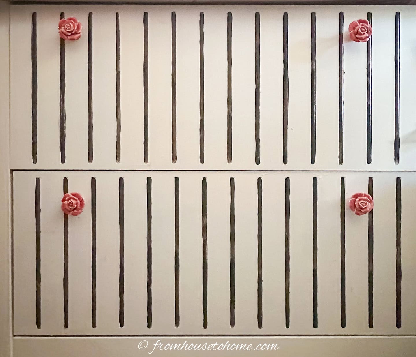A filing cabinet that has been painted white with black pinstripes and ceramic rose knobs