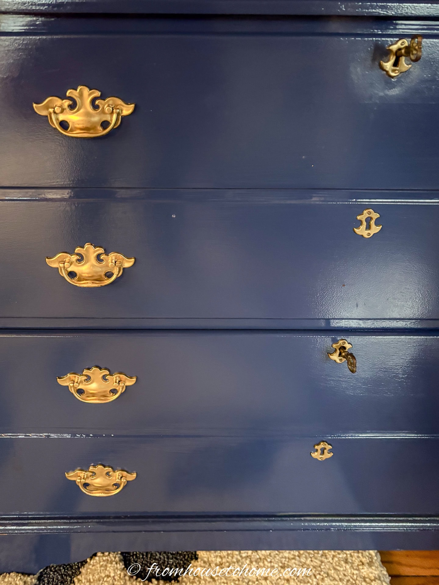The front of a painted navy blue bookshelf with handles that have been spray painted gold