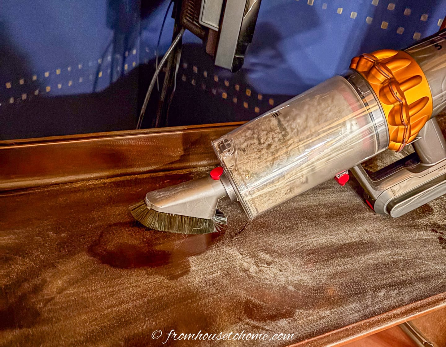 a hand vacuum cleaning up sawdust on a sanded bookshelf