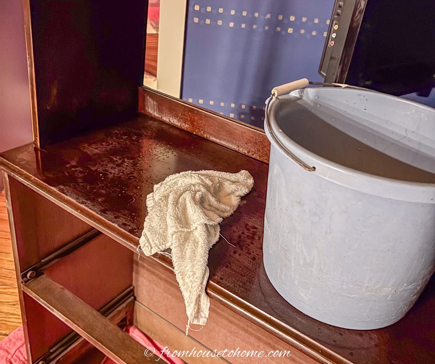 damp cloth and a pail of water on a bookshelf being refinished