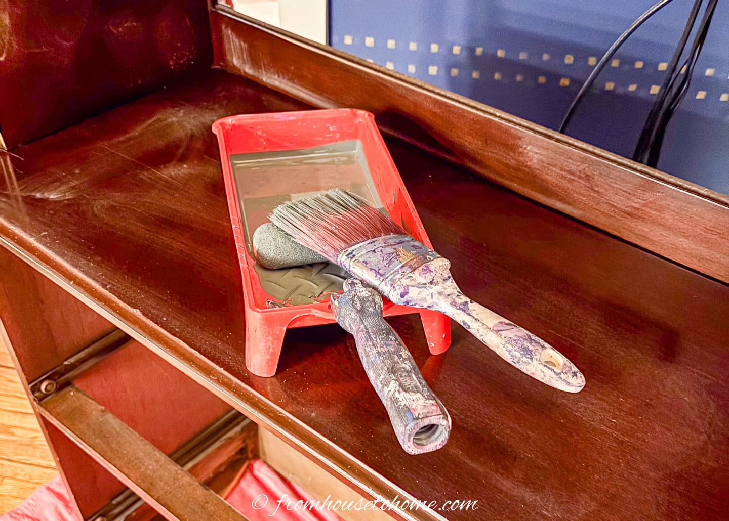 paint tray filled with gray primer, a small roller and a brush