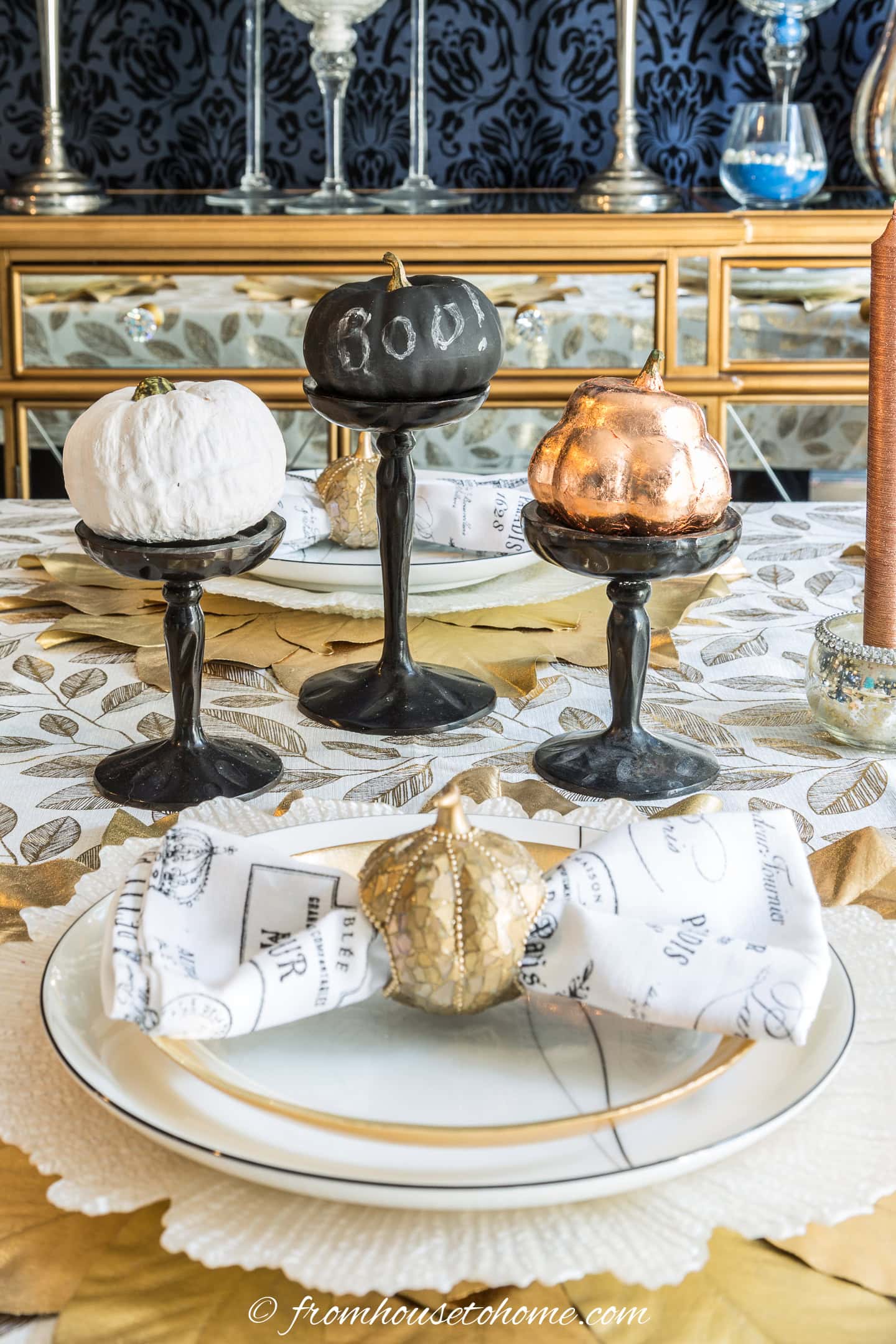 a black and a white spray painted faux pumpkins in a centerpiece on a fall tablescape