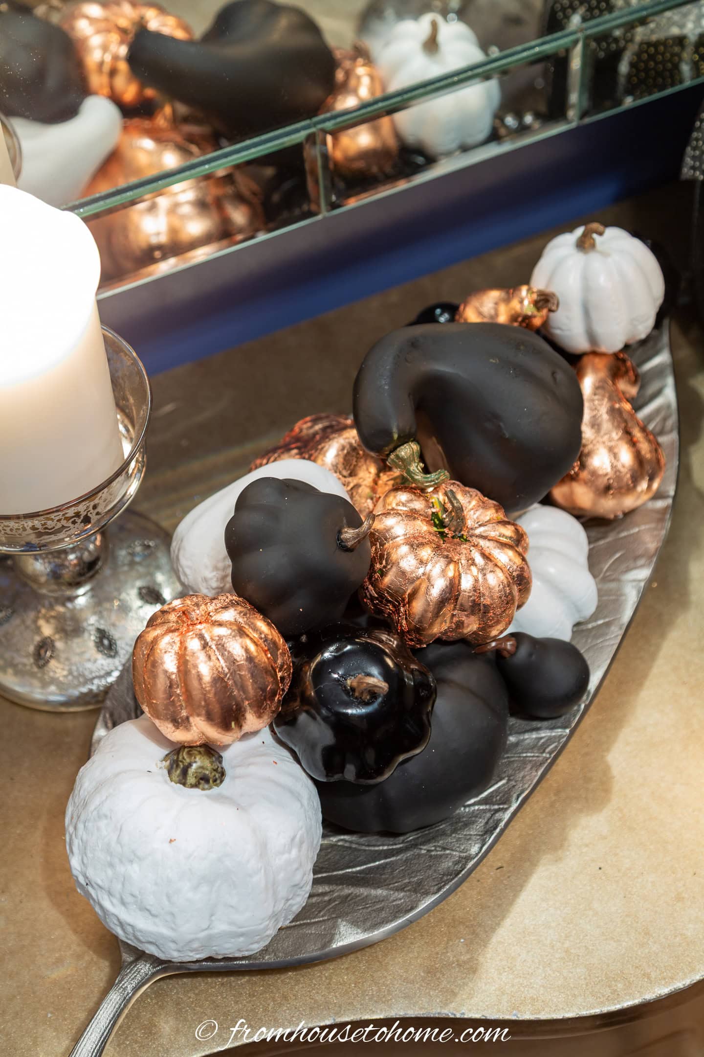 Black and white spray painted faux pumpkins in a silver leaf tray with copper leaf pumpkins
