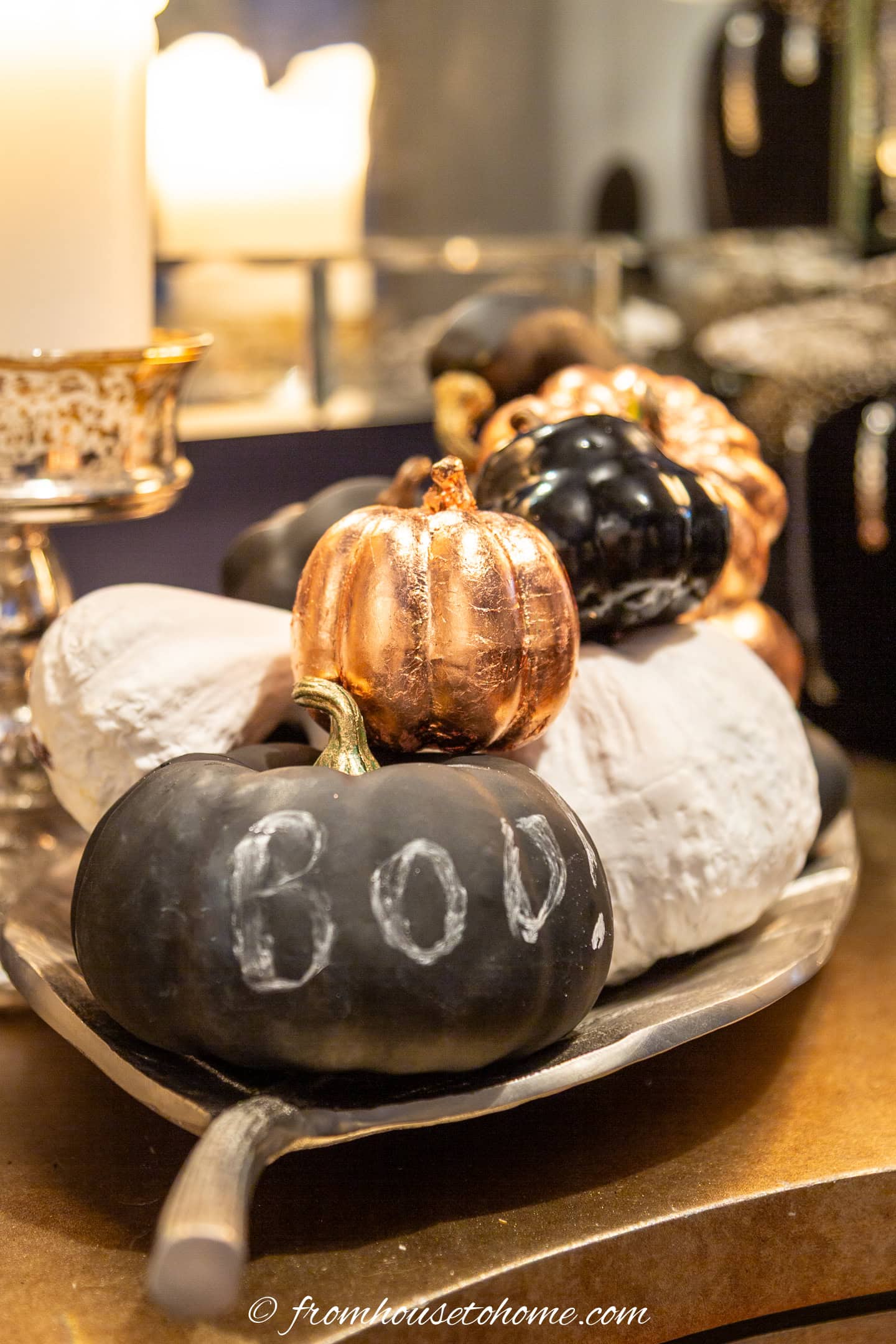 A group of spray painted faux pumpkins in a silver leaf tray with copper leaf pumpkins
