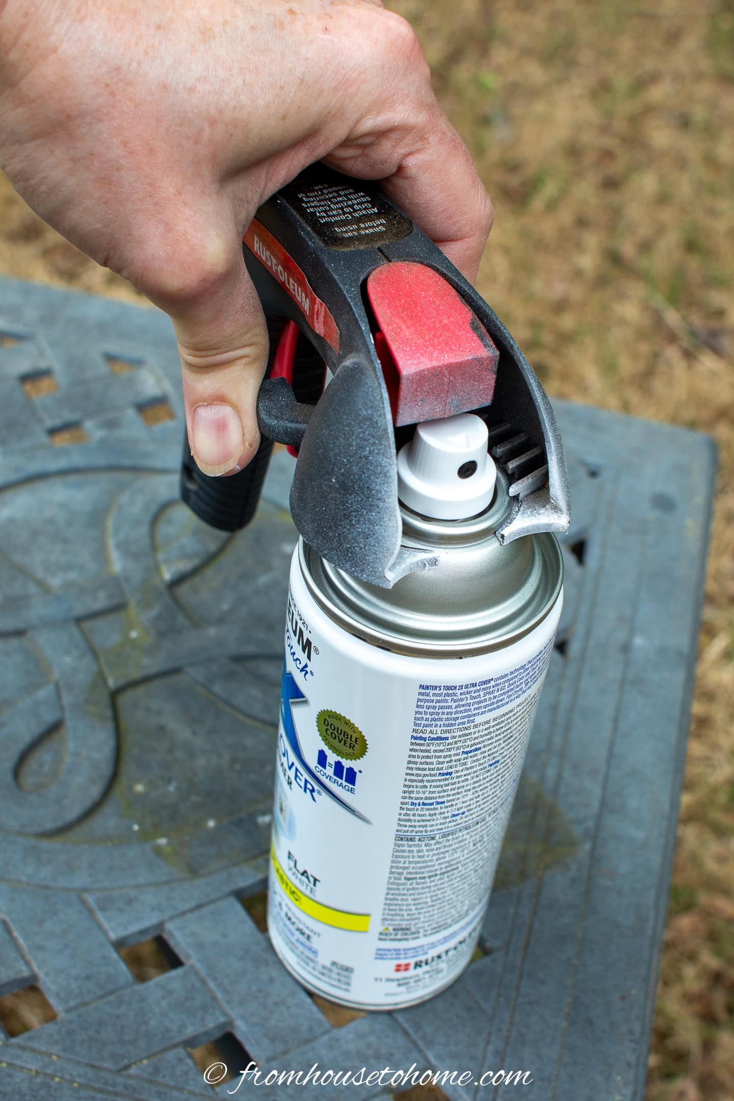 A spray paint can with a spray gun being attached to the top of it