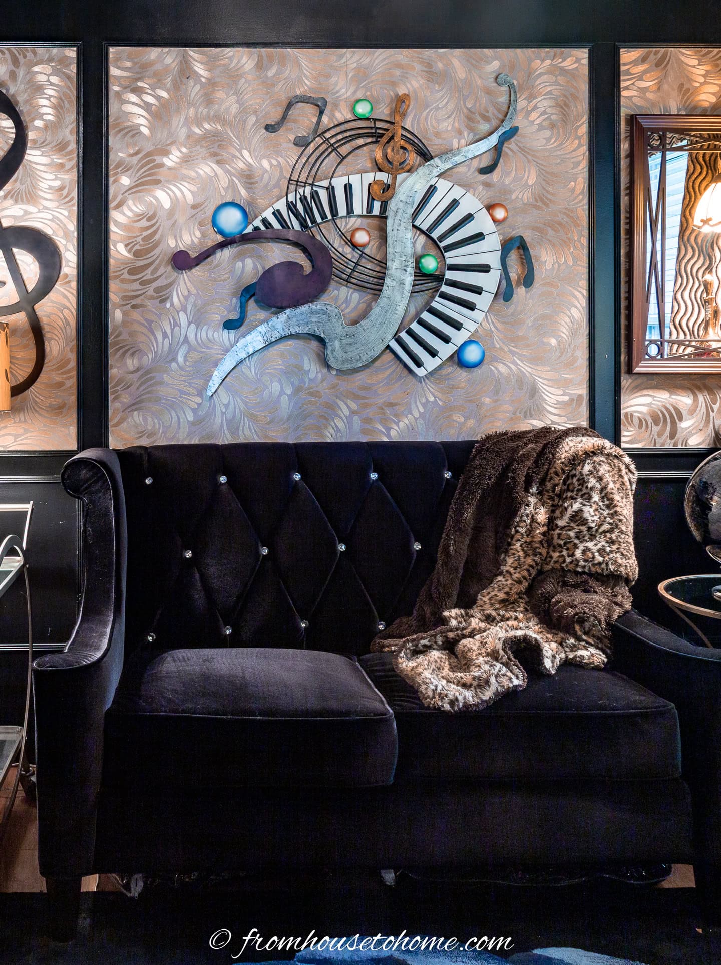 A black sofa with gold wallpapered panelling behind it