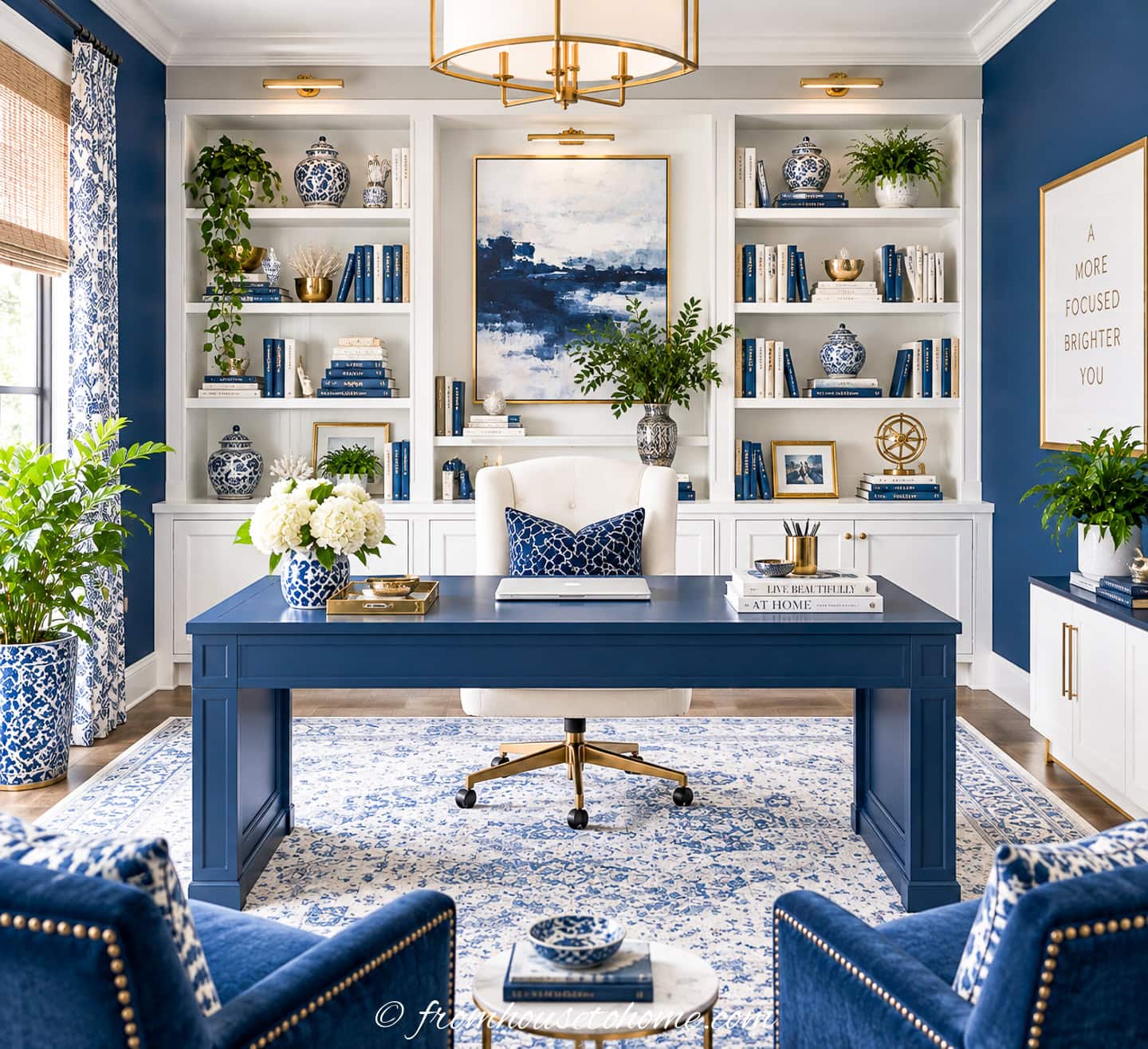 A blue and white home office with a white bookshelf across the back wall