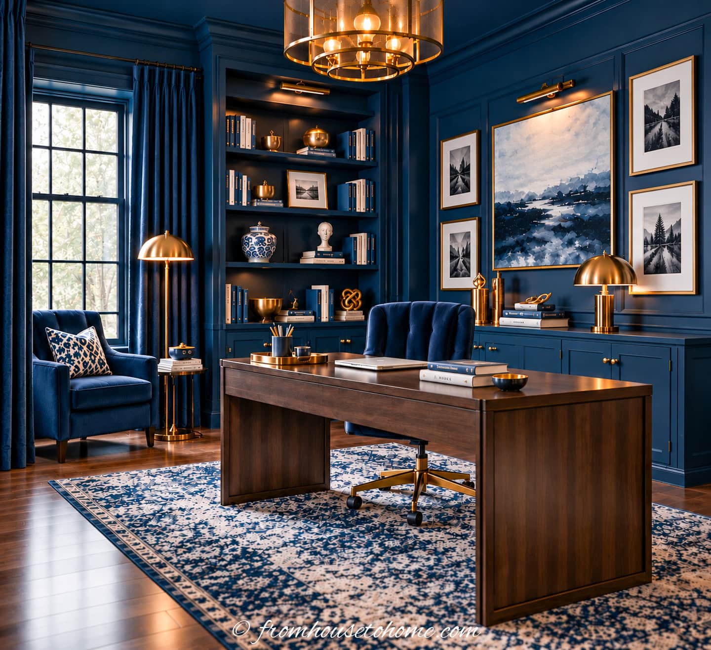 A home office with navy blue walls, ceiling and curtains, a large wood desk and gold accents
