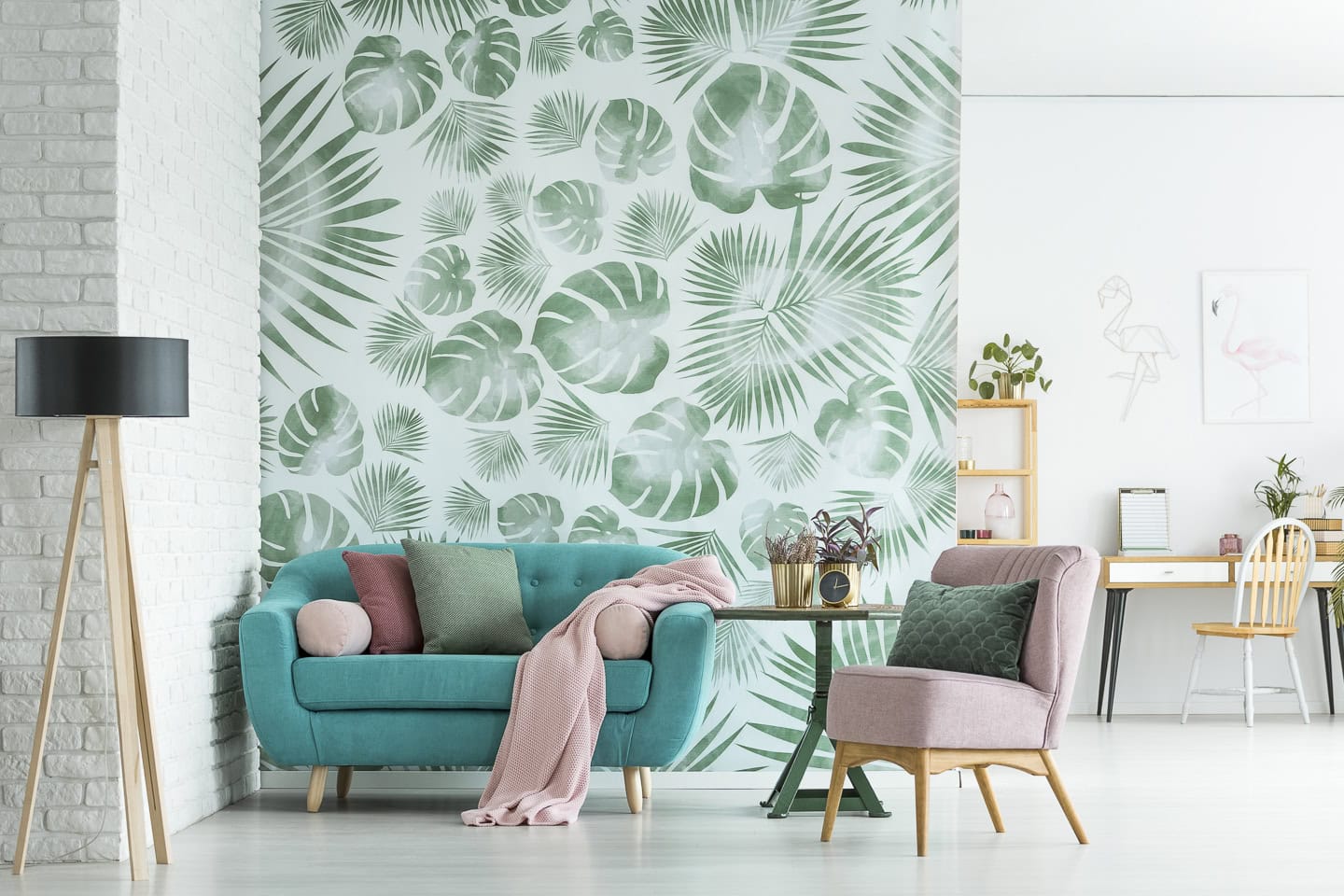 A partial wall behind a sofa in a living room covered with a green leaf wallpaper