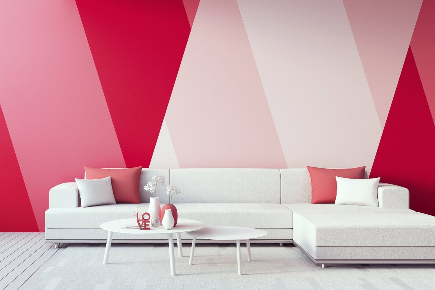 A white sofa in front of an accent wall painted with shades of red and pink