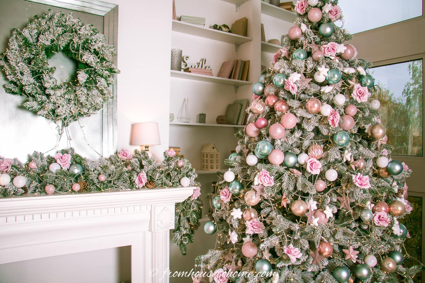 A Christmas tree decorated with pink and teal ornamnets and pink flowers