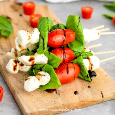 A stack of caprese skewers on a wood cutting board